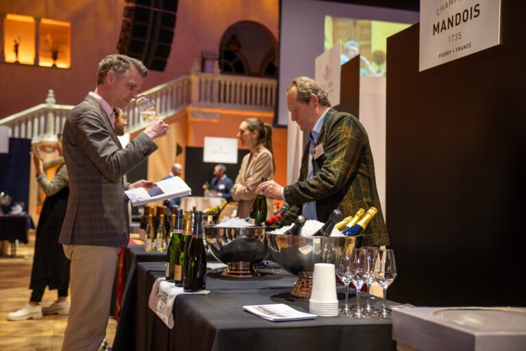 Exhibitors pouring and tasting champagne at a stand at a wine and champagne fair
